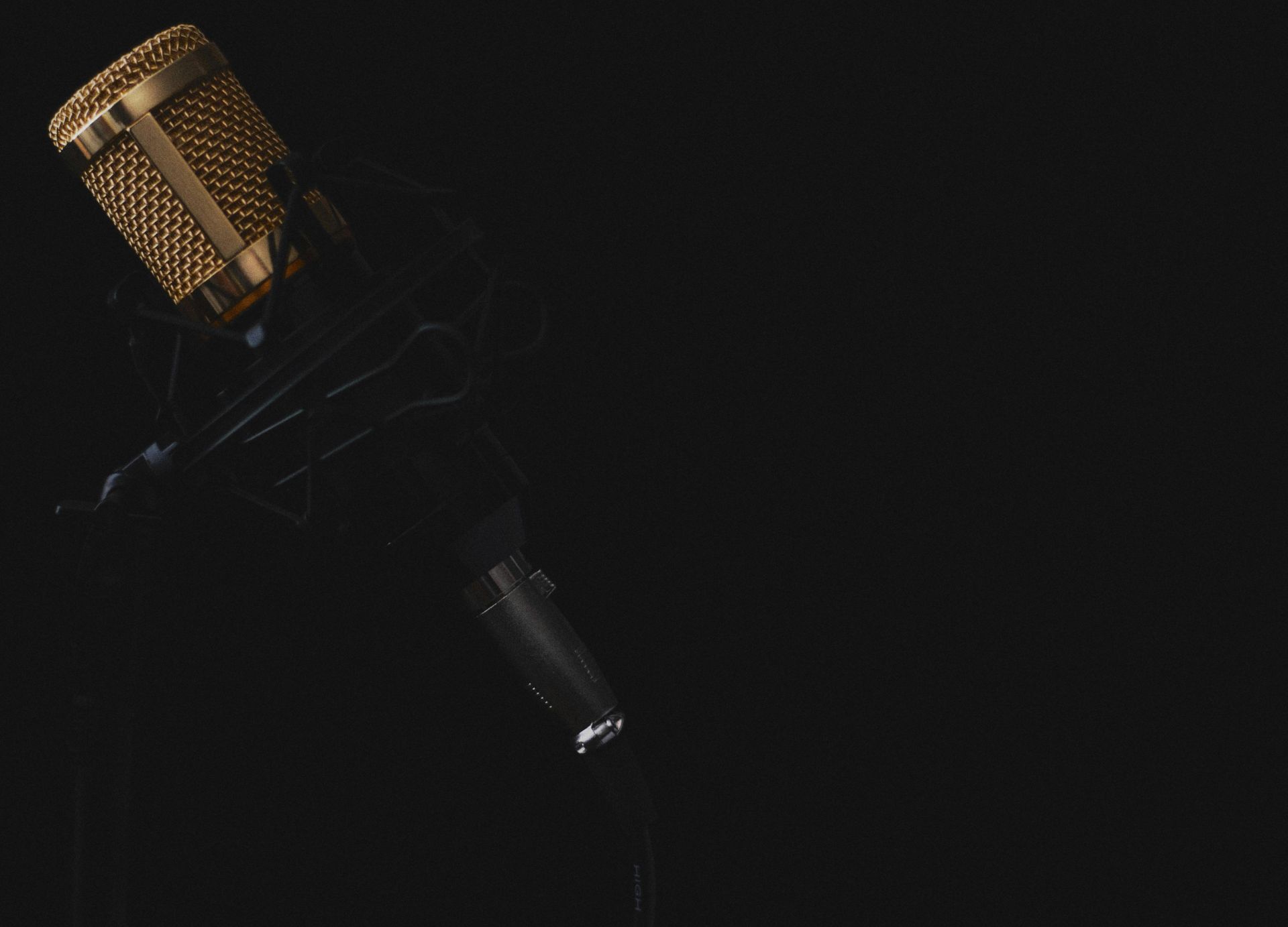 Elegant golden microphone against a dark backdrop, perfect for recording studio illustrations.